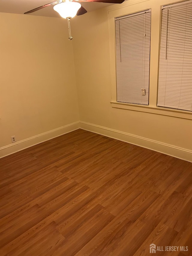 empty room featuring dark wood-style floors, ceiling fan, and baseboards