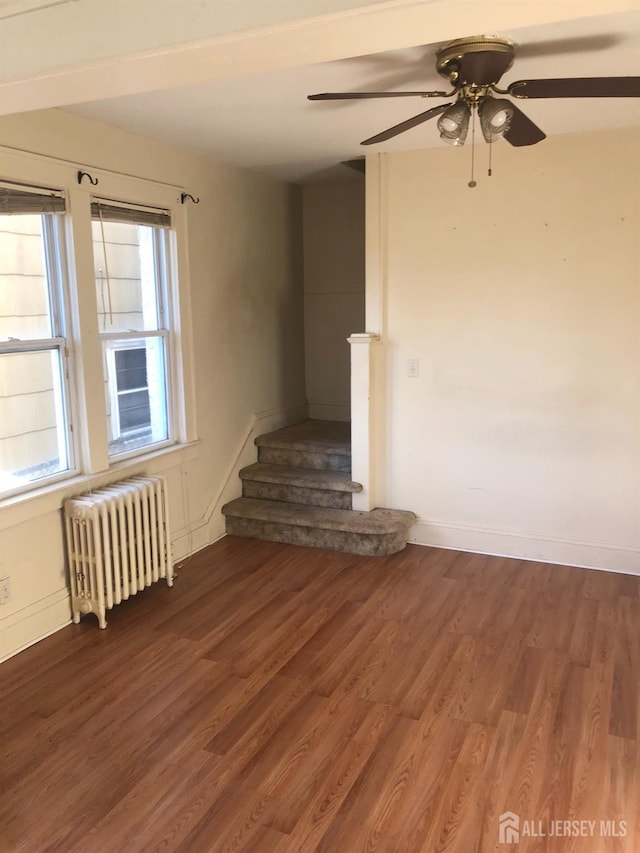 interior space with radiator heating unit, wood finished floors, a ceiling fan, and baseboards