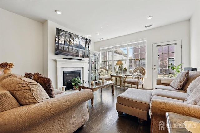 living area featuring dark wood-style floors, recessed lighting, visible vents, and a fireplace