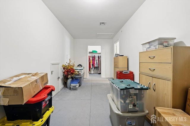 corridor featuring attic access, visible vents, and concrete floors