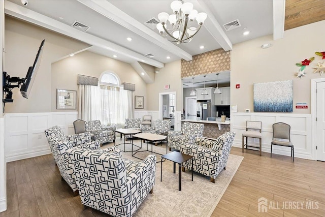 living area featuring wood finished floors, visible vents, high vaulted ceiling, and beam ceiling