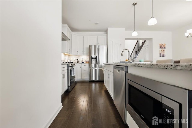 kitchen featuring dark wood-type flooring, pendant lighting, tasteful backsplash, appliances with stainless steel finishes, and white cabinetry