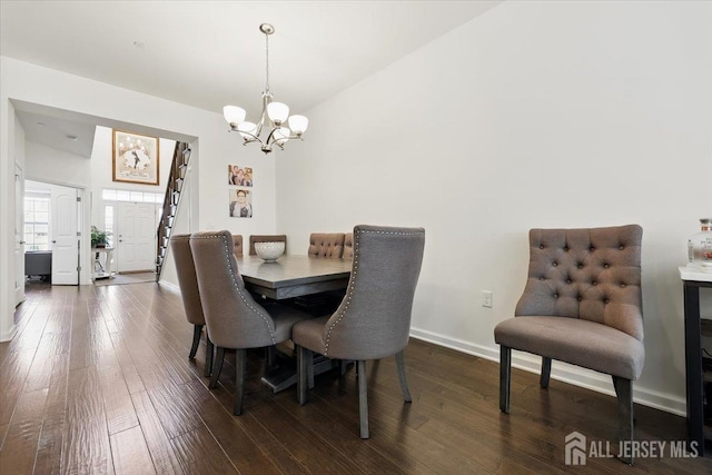 dining area with a chandelier, dark wood-style floors, baseboards, and lofted ceiling