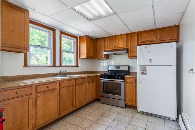 kitchen with sink, stainless steel gas stove, a paneled ceiling, white fridge, and a baseboard heating unit