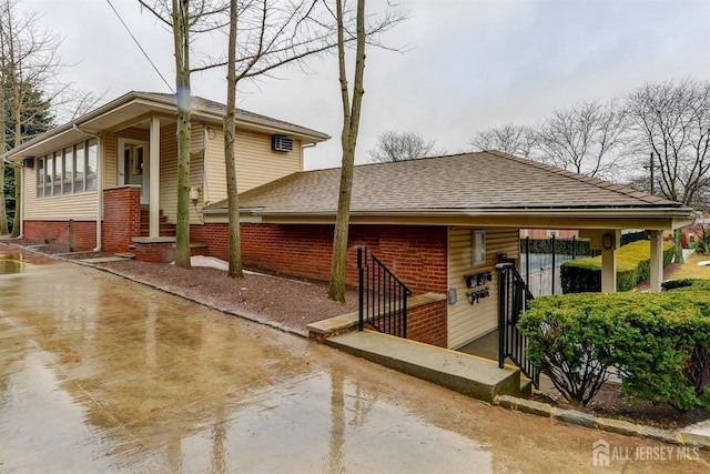 view of side of property featuring brick siding and roof with shingles