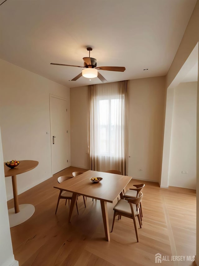 dining area featuring baseboards, light wood-style flooring, and a ceiling fan