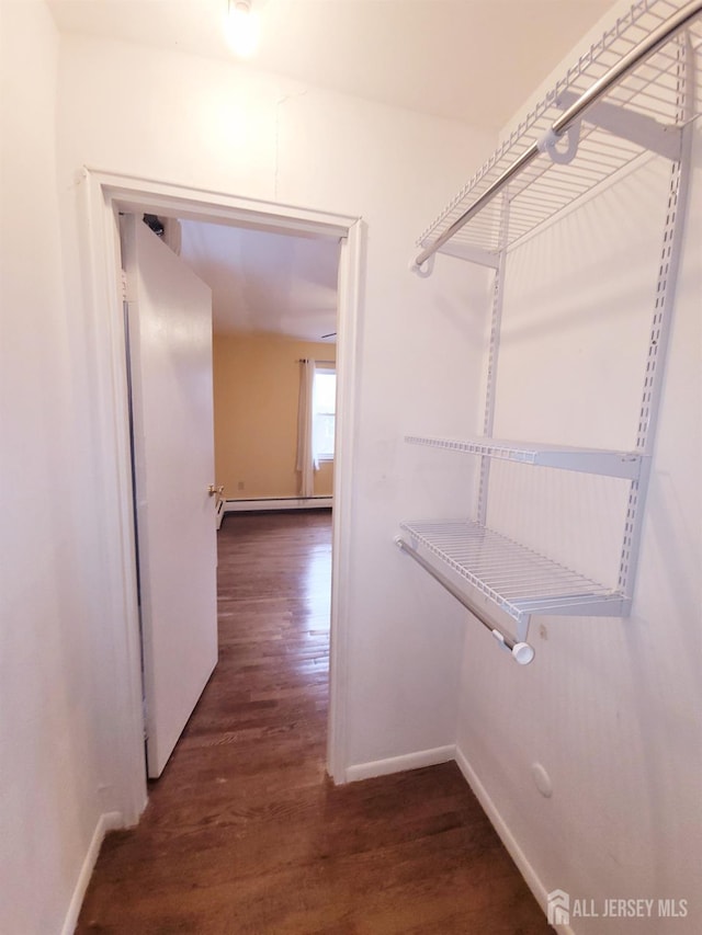 walk in closet featuring baseboard heating and dark wood-style flooring