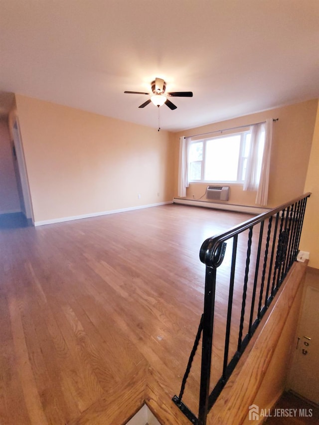 spare room with baseboards, wood finished floors, and a ceiling fan