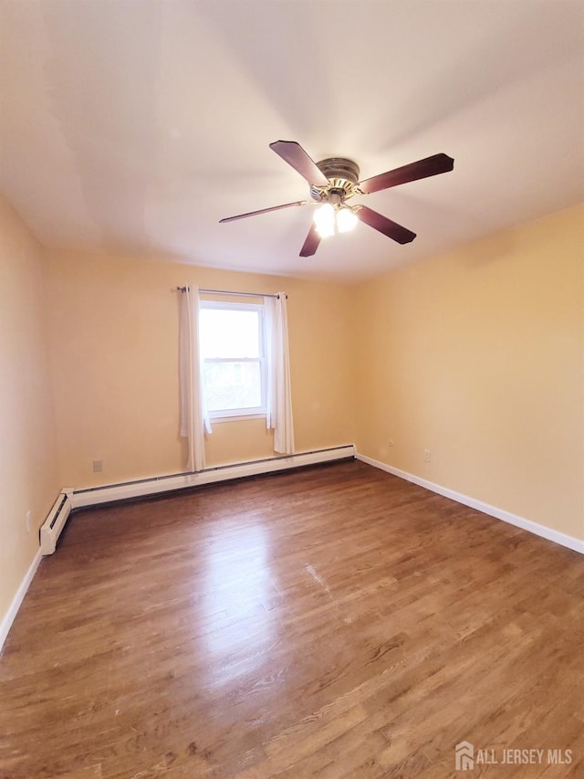 spare room with wood finished floors, a ceiling fan, baseboards, and a baseboard radiator