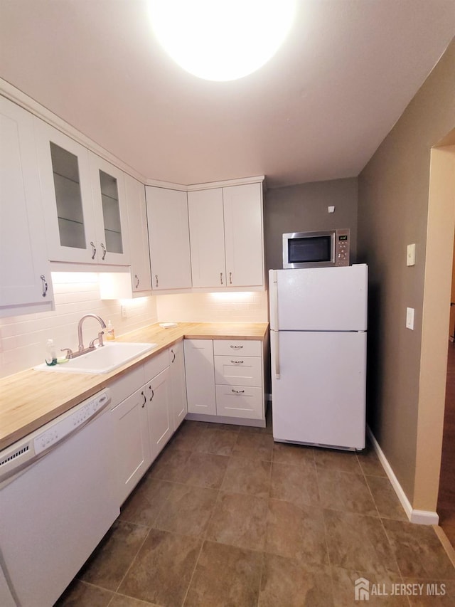 kitchen featuring white appliances, white cabinets, glass insert cabinets, and a sink