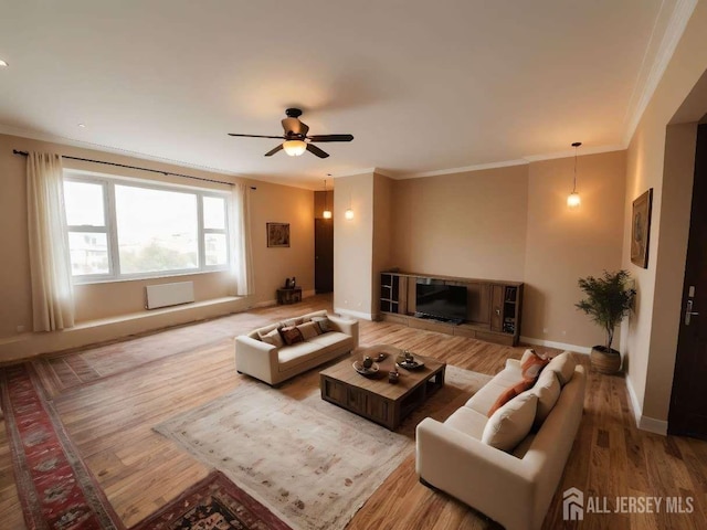 living room with a glass covered fireplace, wood finished floors, baseboards, and ornamental molding