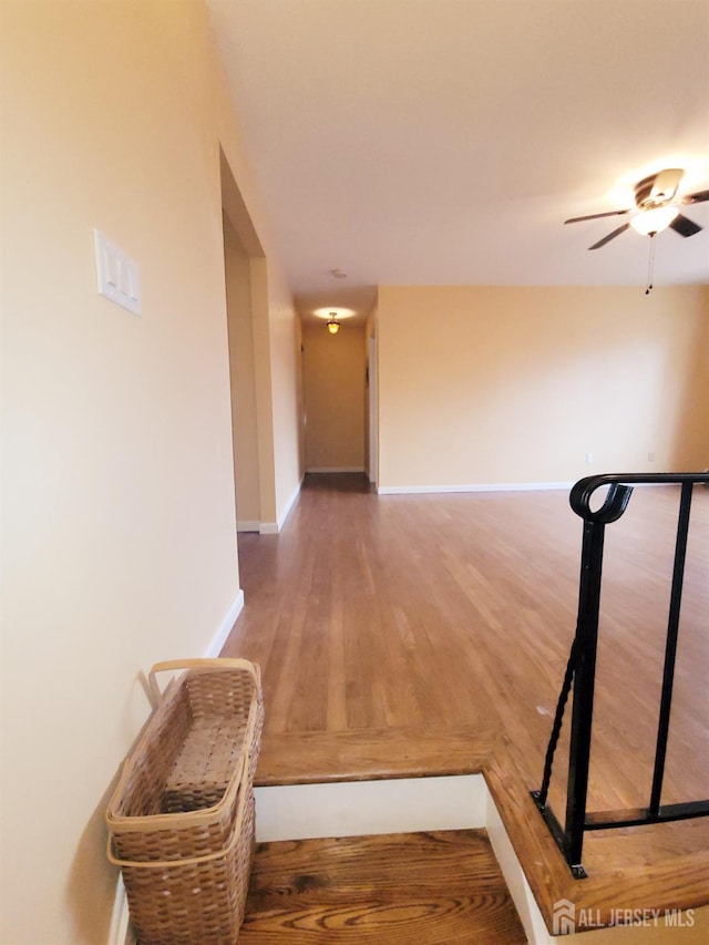 hall with baseboards and wood finished floors