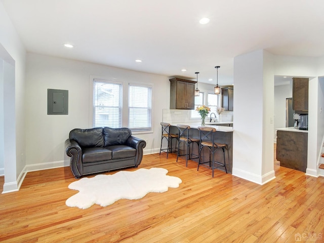 living room with sink, electric panel, and light hardwood / wood-style floors