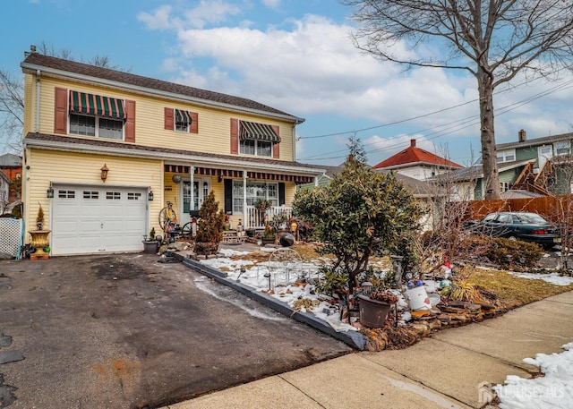 traditional home featuring aphalt driveway, a garage, covered porch, and fence