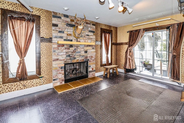 unfurnished living room with wallpapered walls, a fireplace, and baseboards