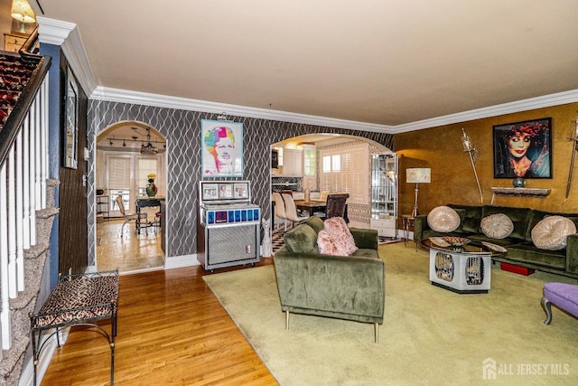 living area featuring wallpapered walls, arched walkways, and ornamental molding