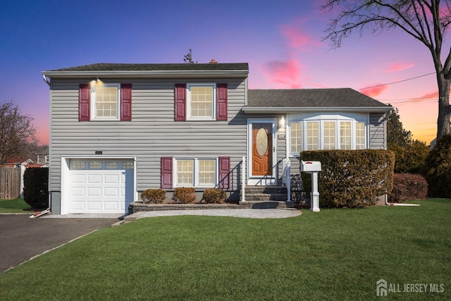 split level home featuring driveway, an attached garage, and a lawn