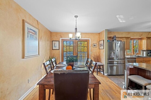 dining room with a chandelier, french doors, light hardwood / wood-style flooring, and sink