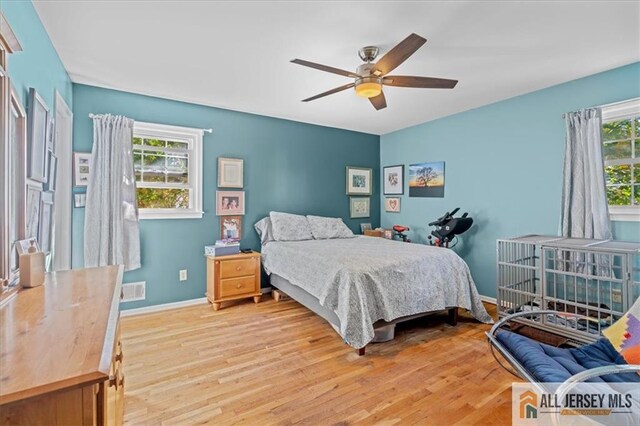 bedroom featuring ceiling fan, multiple windows, and light hardwood / wood-style flooring