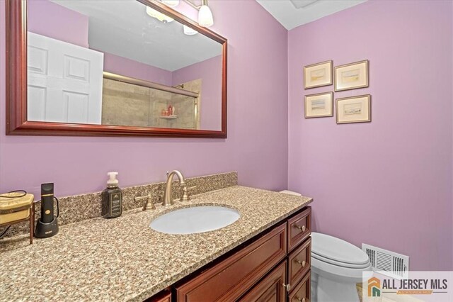 bathroom with an enclosed shower, vanity, and toilet