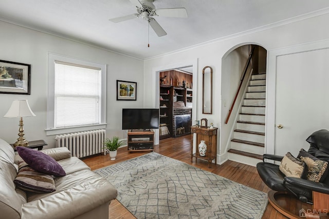 living area with stairs, radiator heating unit, hardwood / wood-style floors, arched walkways, and a ceiling fan