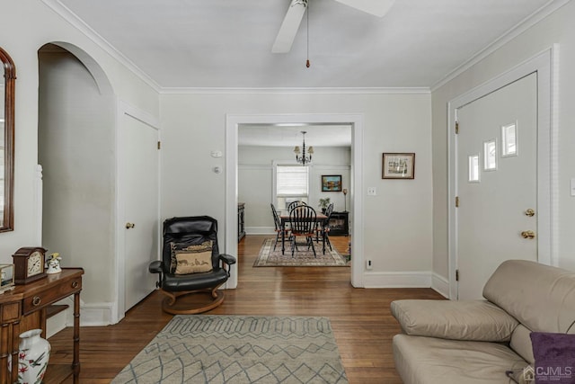 living room featuring dark wood-type flooring, a ceiling fan, arched walkways, crown molding, and baseboards