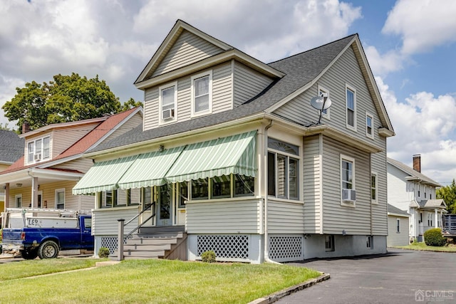 view of front of property with entry steps, a front lawn, and roof with shingles