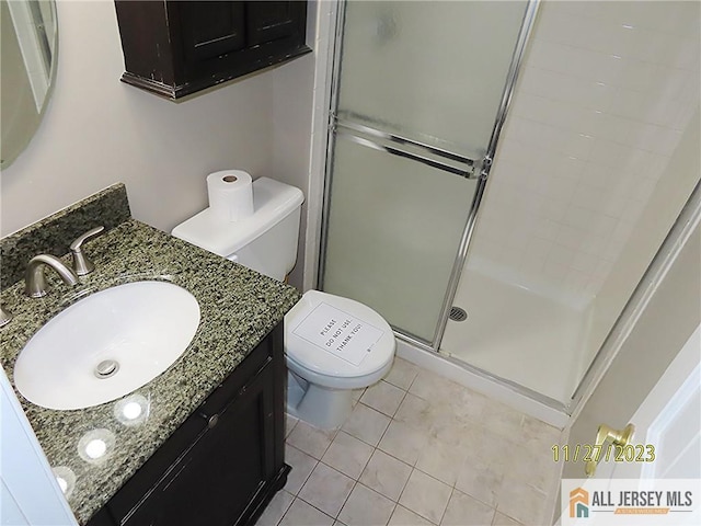 bathroom with tile patterned flooring, vanity, toilet, and a shower with door