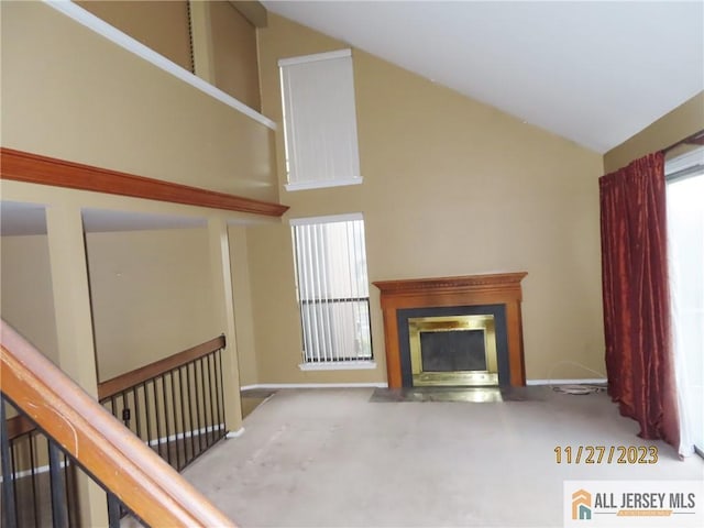 unfurnished living room featuring carpet floors and high vaulted ceiling