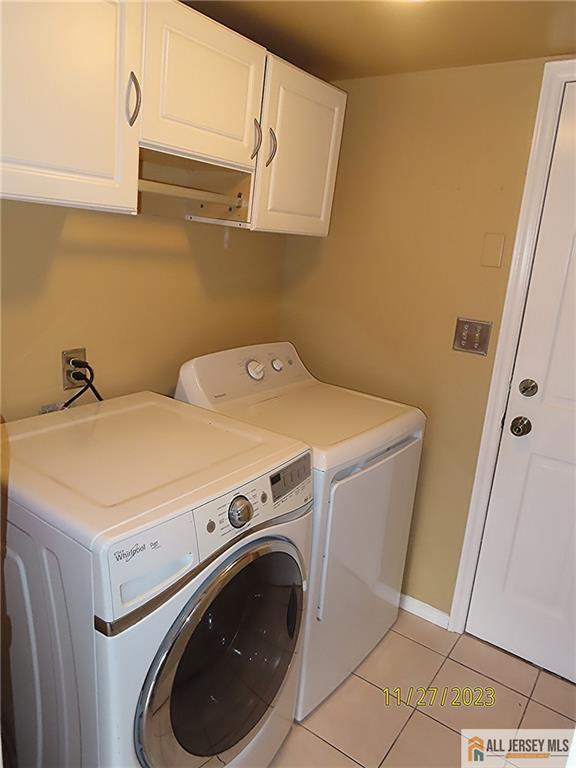 washroom with cabinets, independent washer and dryer, and light tile patterned floors