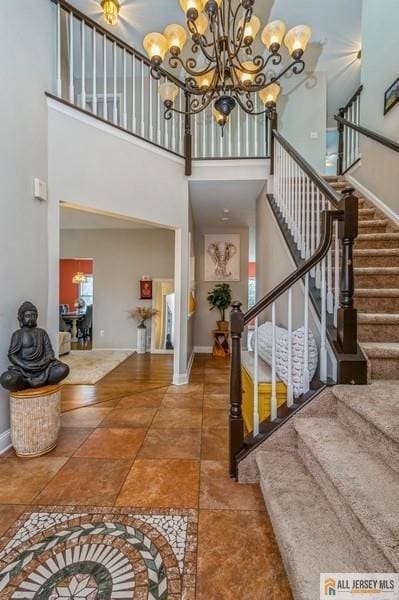 foyer featuring a notable chandelier, a high ceiling, stairs, and baseboards