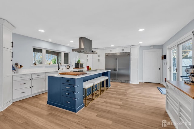 kitchen with a kitchen island, extractor fan, built in fridge, white cabinetry, and blue cabinets