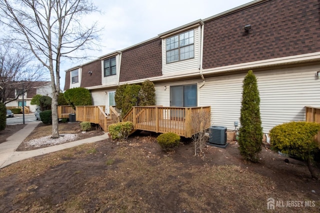 rear view of property featuring a deck, mansard roof, a shingled roof, and central air condition unit