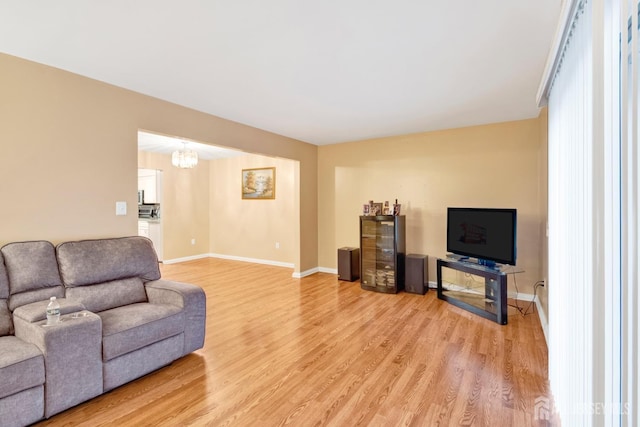 living room featuring an inviting chandelier, light wood-style flooring, and baseboards