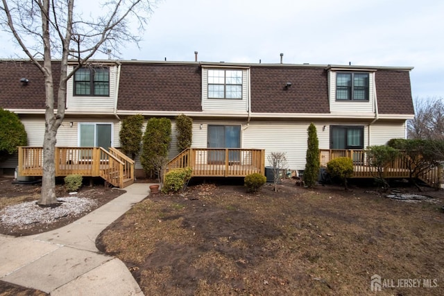 rear view of house with a shingled roof, central air condition unit, a deck, and mansard roof