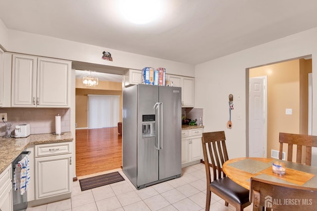 kitchen featuring light tile patterned flooring, visible vents, white cabinets, backsplash, and stainless steel fridge with ice dispenser