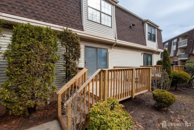 back of property featuring a wooden deck, mansard roof, and roof with shingles