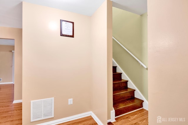 stairway with baseboards, visible vents, and wood finished floors