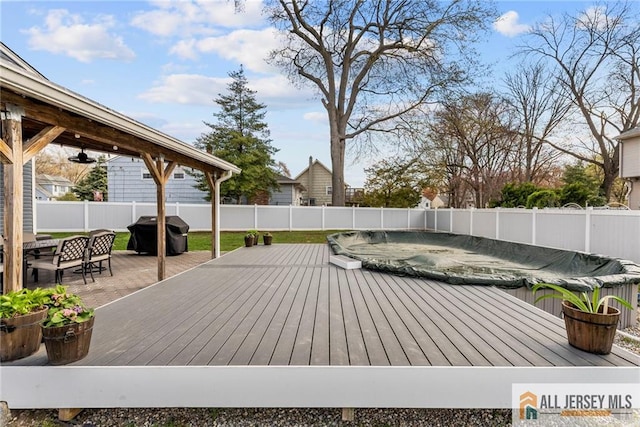 deck with outdoor dining area, a grill, a fenced in pool, and a fenced backyard