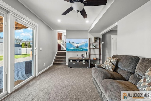 carpeted living area with a ceiling fan, baseboards, and stairway