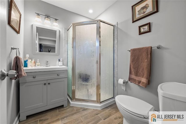 bathroom featuring a stall shower, vanity, toilet, and wood finished floors