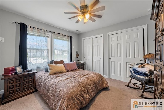 bedroom featuring ceiling fan, light carpet, and two closets