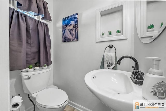 bathroom featuring a sink, toilet, and baseboards