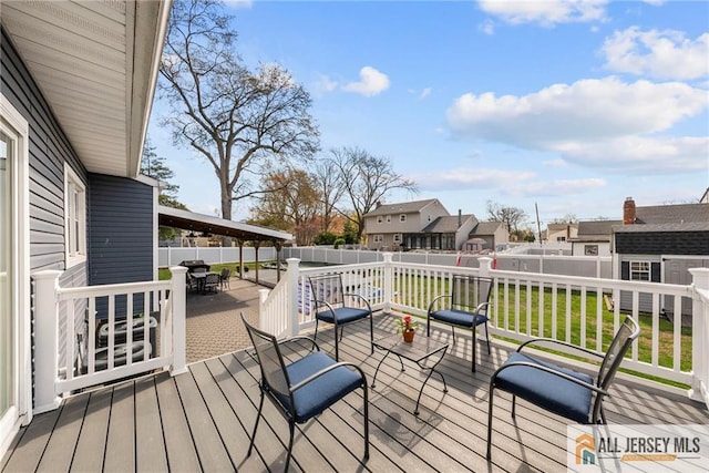 deck featuring a yard, outdoor dining space, a residential view, and a fenced backyard