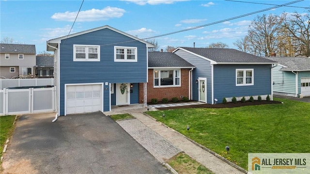 split level home with a front yard, aphalt driveway, a garage, and fence