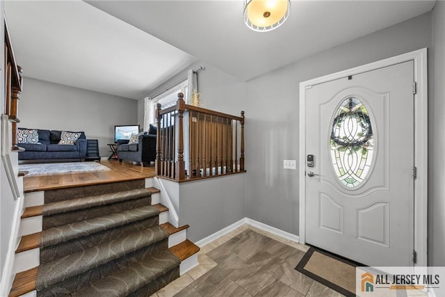 foyer entrance with baseboards and stairway