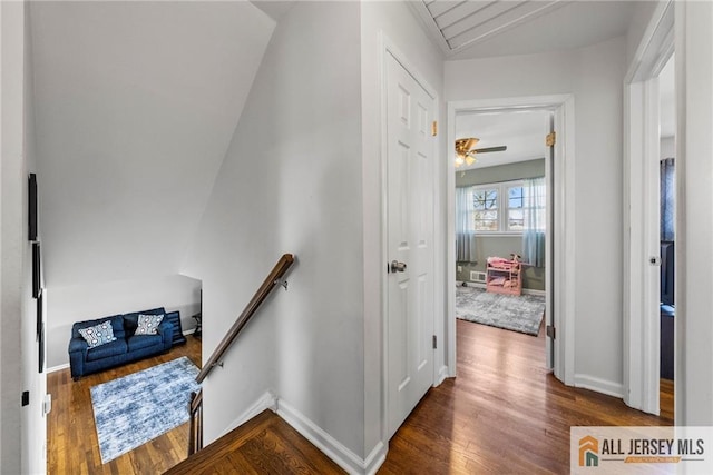 interior space with vaulted ceiling, baseboards, an upstairs landing, and wood finished floors