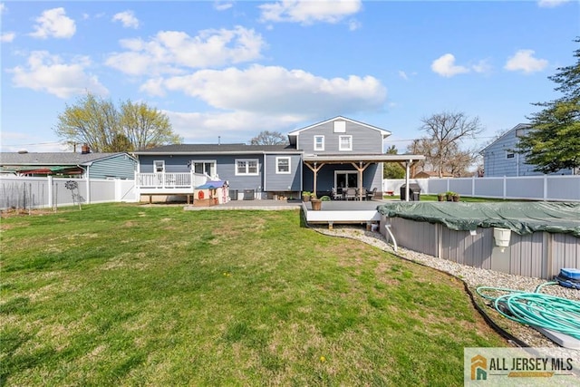 back of house with a lawn, a fenced in pool, a patio, a deck, and a fenced backyard