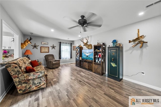 living area with a ceiling fan, baseboards, visible vents, and wood finished floors