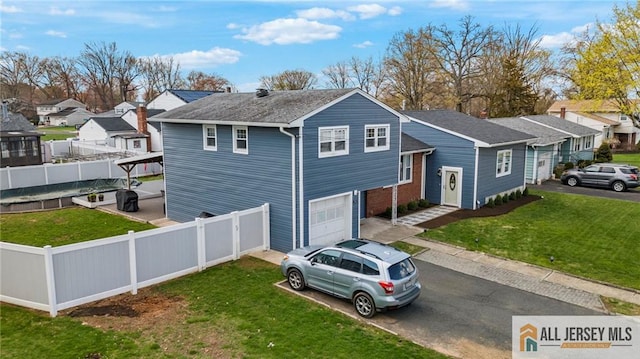 view of front of property featuring fence private yard, a garage, a front lawn, and driveway
